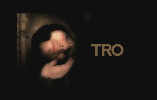 TRO looking through a hole at an angle, with the text of his artist name on the right to his head