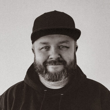 profile photo of artist Dave Mono wearing a black plain baseball cap and hoody