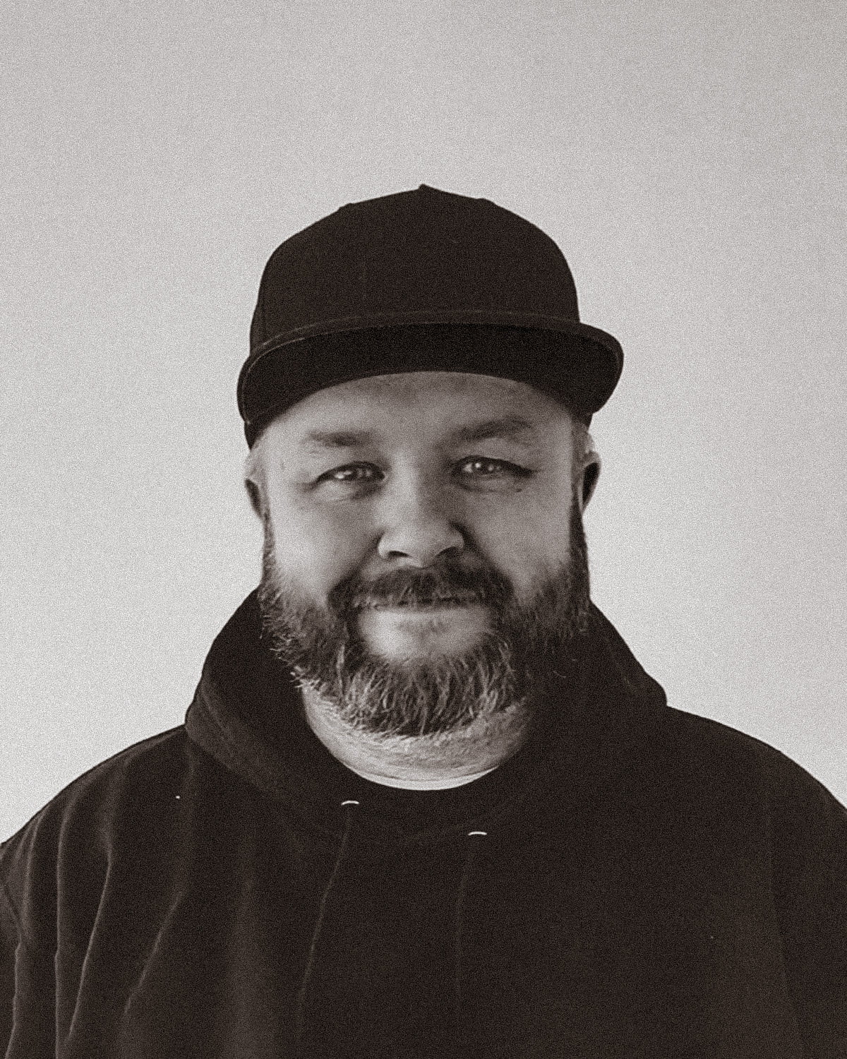 profile photo of artist Dave Mono wearing a black plain baseball cap and hoody